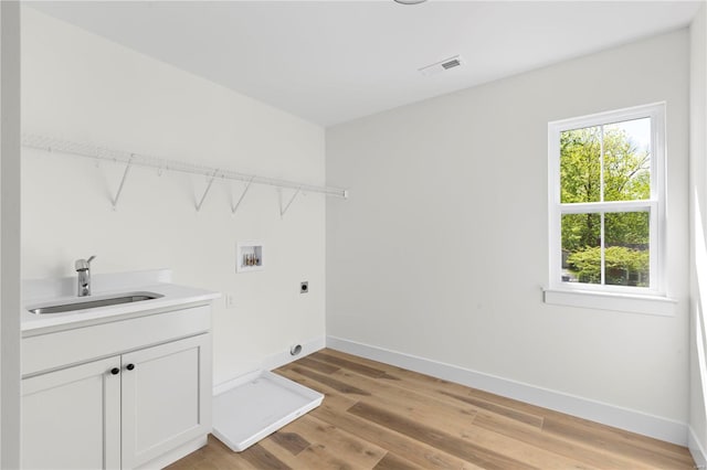 washroom with cabinets, hookup for a washing machine, electric dryer hookup, sink, and light hardwood / wood-style flooring