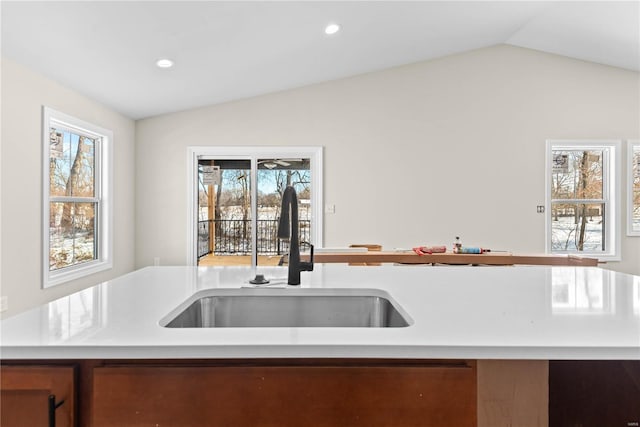 kitchen featuring lofted ceiling, a center island with sink, and sink