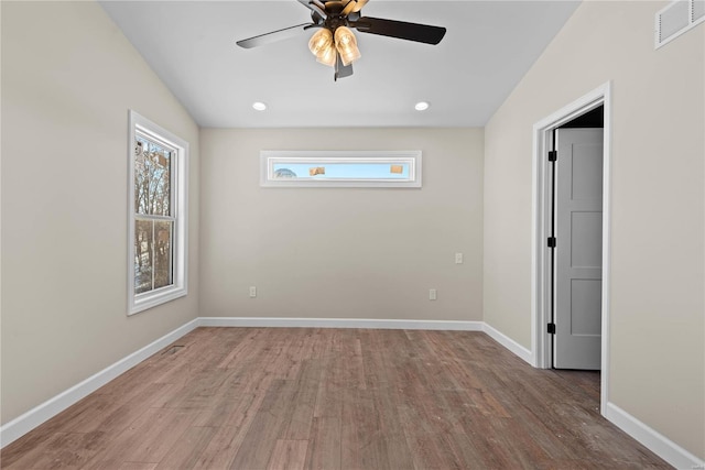 empty room with ceiling fan, a wealth of natural light, and hardwood / wood-style flooring