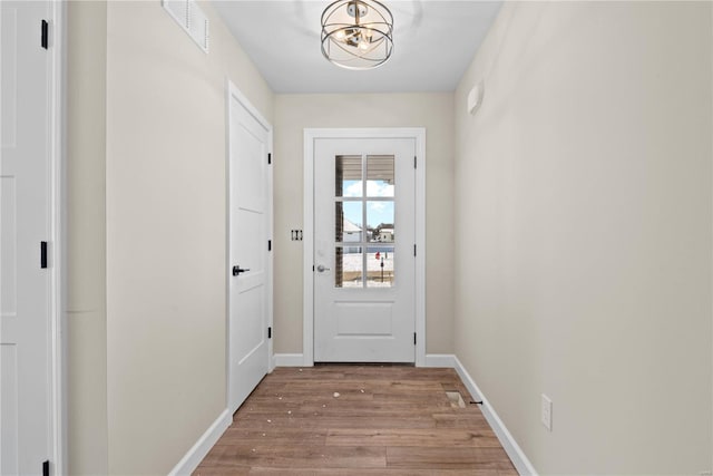 doorway with a notable chandelier and light hardwood / wood-style flooring