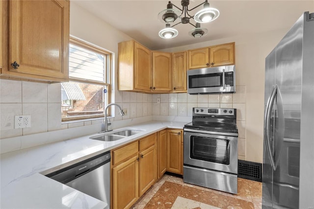 kitchen with decorative backsplash, stainless steel appliances, light stone countertops, and sink