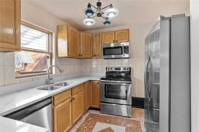 kitchen featuring decorative backsplash, sink, appliances with stainless steel finishes, and an inviting chandelier