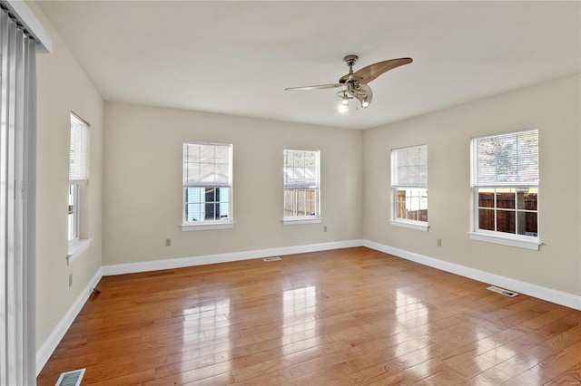 empty room with a wealth of natural light, ceiling fan, and light hardwood / wood-style floors