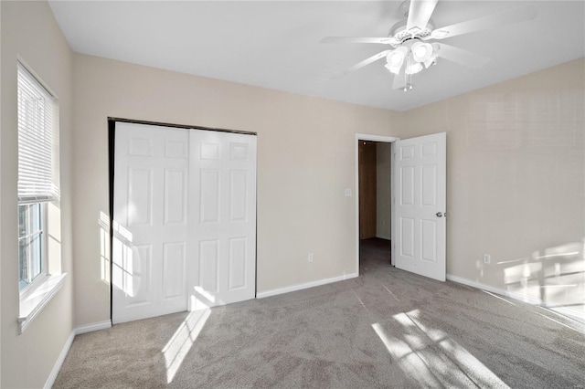 unfurnished bedroom featuring ceiling fan, a closet, light colored carpet, and multiple windows