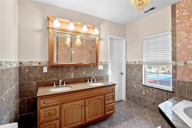 bathroom featuring tile patterned floors, a bathtub, vanity, and tile walls