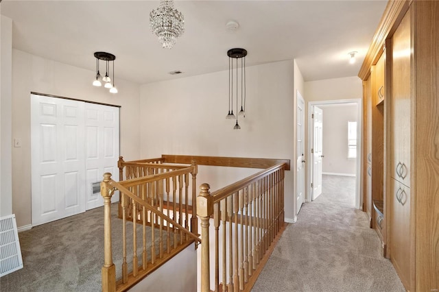 hall with carpet floors and an inviting chandelier