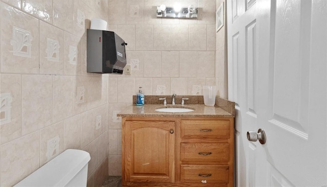 bathroom with vanity, toilet, and tile walls