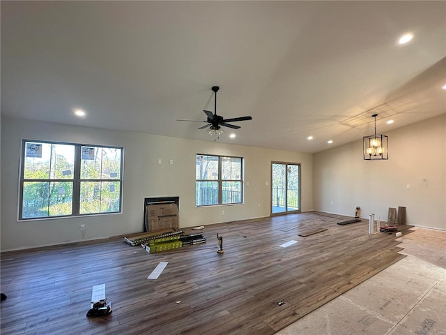 unfurnished living room with ceiling fan with notable chandelier, a healthy amount of sunlight, and wood-type flooring