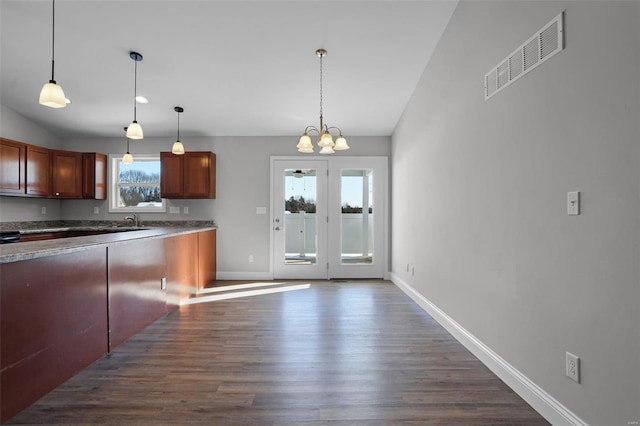 kitchen featuring a healthy amount of sunlight, hanging light fixtures, a notable chandelier, and dark hardwood / wood-style flooring