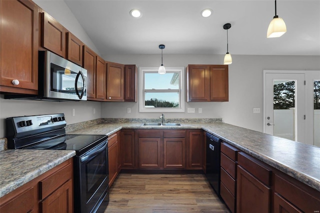 kitchen with black appliances, hanging light fixtures, kitchen peninsula, dark wood-type flooring, and sink