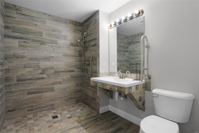 bathroom featuring wood-type flooring, a tile shower, and toilet