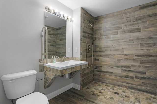 bathroom featuring a tile shower, hardwood / wood-style flooring, and toilet