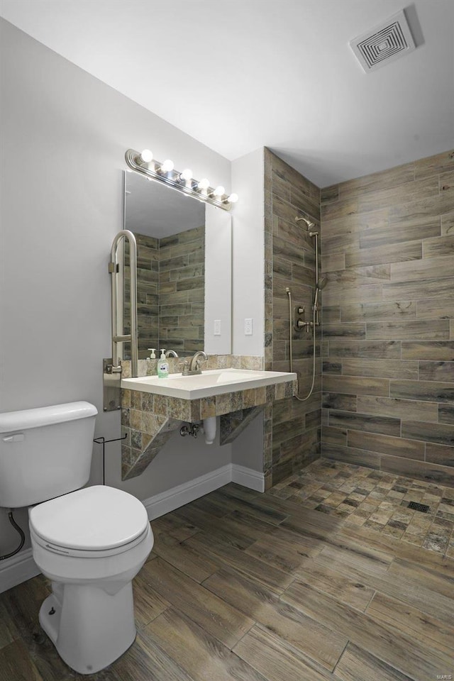 bathroom featuring tiled shower and toilet