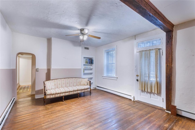 living area with hardwood / wood-style floors, ceiling fan, a baseboard heating unit, and beam ceiling