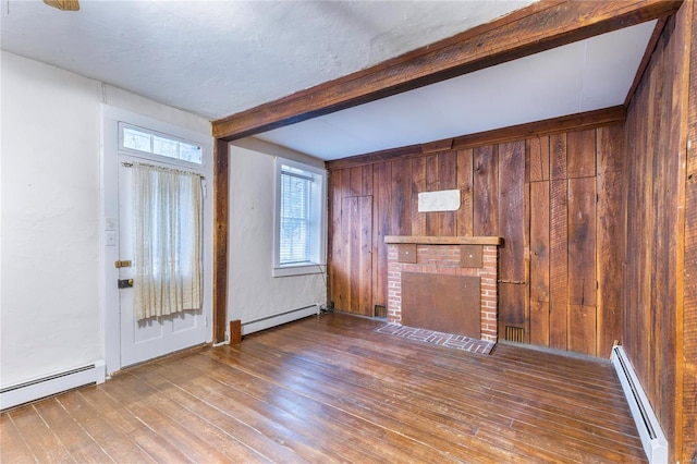 unfurnished living room with hardwood / wood-style floors, a baseboard radiator, and wooden walls