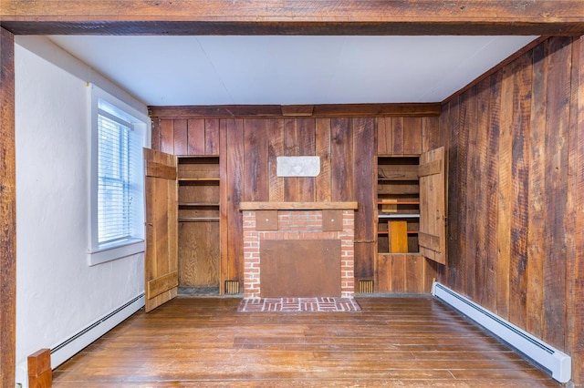 unfurnished living room featuring baseboard heating, a brick fireplace, wooden walls, and hardwood / wood-style flooring