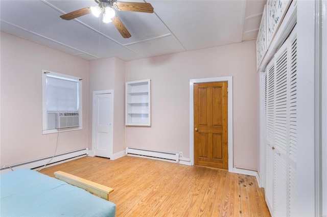 unfurnished bedroom featuring wood-type flooring, a baseboard radiator, ceiling fan, and cooling unit