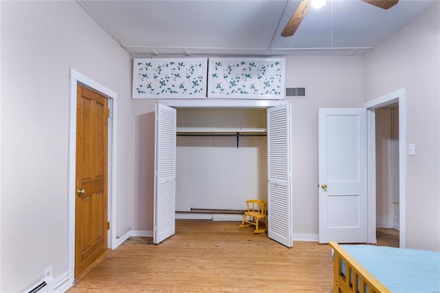 bedroom with ceiling fan, light hardwood / wood-style floors, a closet, and a baseboard radiator