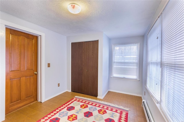 bedroom featuring multiple windows, a textured ceiling, a baseboard radiator, and a closet