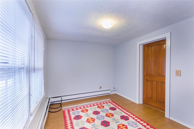 unfurnished room with a textured ceiling, baseboard heating, and light hardwood / wood-style flooring