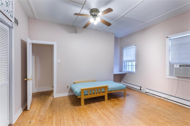 bedroom with cooling unit, light hardwood / wood-style flooring, ceiling fan, and a baseboard heating unit