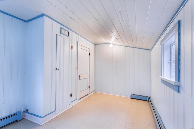 empty room featuring a baseboard radiator, wooden ceiling, and wood walls