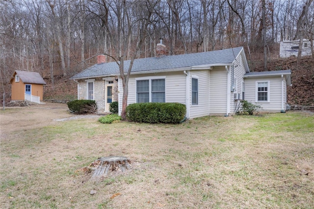 ranch-style house featuring cooling unit, a front lawn, and a storage unit