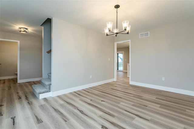 empty room with a chandelier and light wood-type flooring