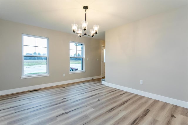 unfurnished room with light hardwood / wood-style floors and a notable chandelier