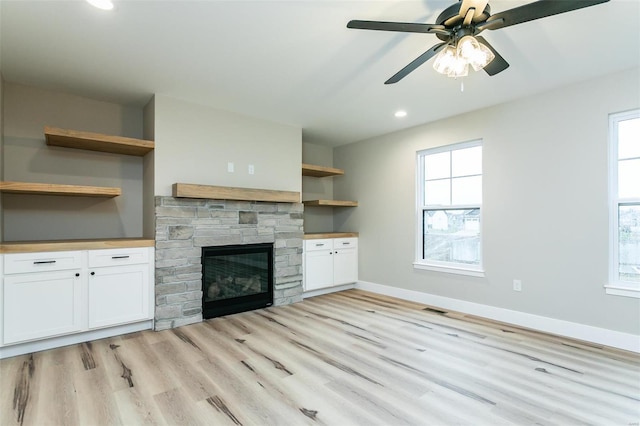 unfurnished living room with ceiling fan, plenty of natural light, a fireplace, and light hardwood / wood-style floors