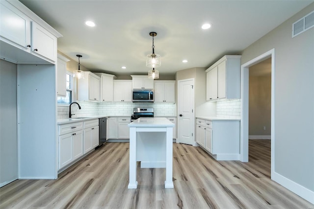 kitchen featuring hanging light fixtures, appliances with stainless steel finishes, sink, and white cabinets