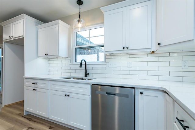 kitchen with white cabinetry, stainless steel dishwasher, light stone countertops, and sink