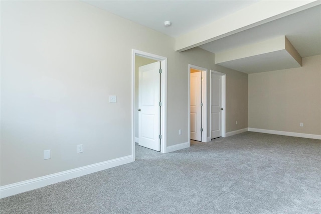 spare room with carpet flooring and beam ceiling