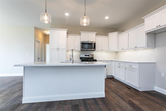 kitchen featuring stainless steel appliances, white cabinetry, pendant lighting, and an island with sink