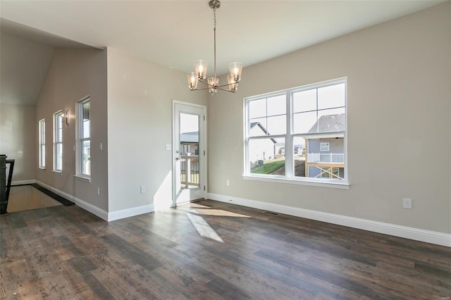 unfurnished dining area with dark hardwood / wood-style floors, a wealth of natural light, and a notable chandelier