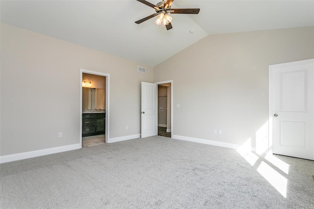 unfurnished bedroom featuring lofted ceiling, connected bathroom, ceiling fan, and carpet