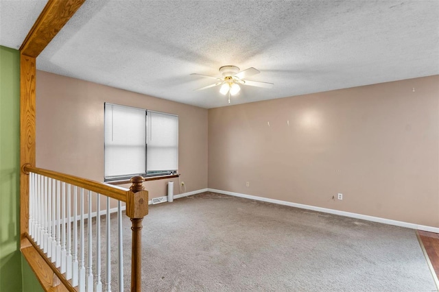 empty room with carpet, ceiling fan, a textured ceiling, and beamed ceiling