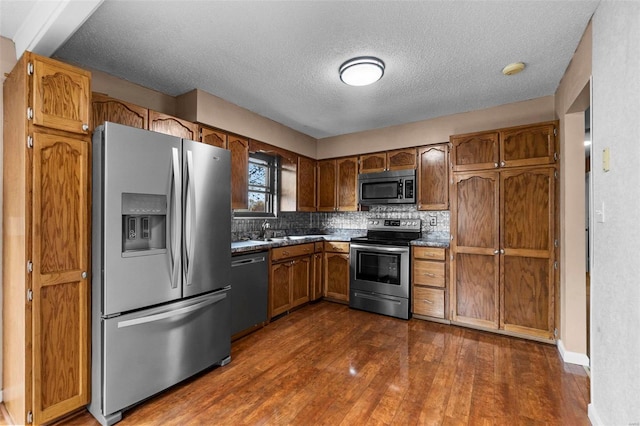 kitchen with tasteful backsplash, dark wood-type flooring, a textured ceiling, and appliances with stainless steel finishes