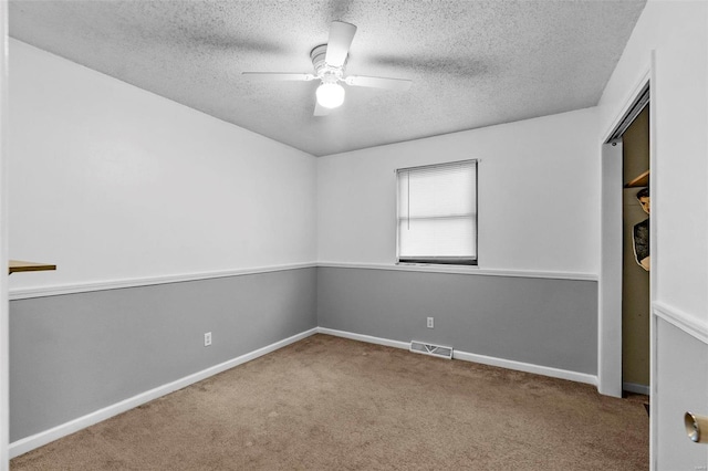 unfurnished room with carpet flooring, ceiling fan, and a textured ceiling