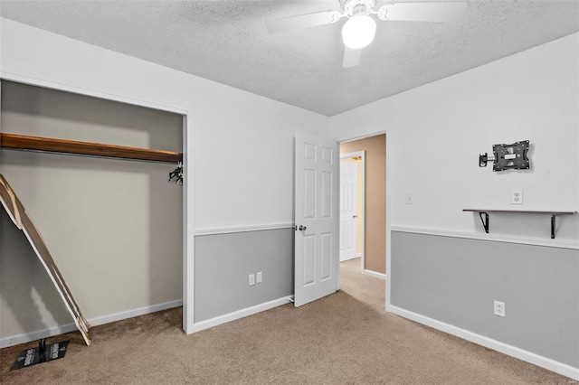 unfurnished bedroom with a closet, a textured ceiling, light colored carpet, and ceiling fan