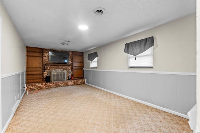 unfurnished living room featuring a textured ceiling, light carpet, wooden walls, and a brick fireplace