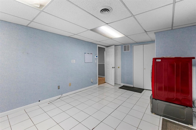 basement featuring a drop ceiling and light tile patterned floors