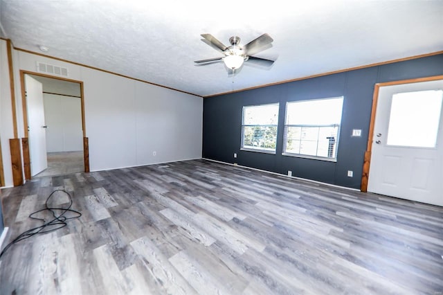 interior space with wood-type flooring, a textured ceiling, ceiling fan, and crown molding