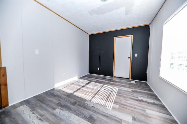 empty room with hardwood / wood-style floors and crown molding