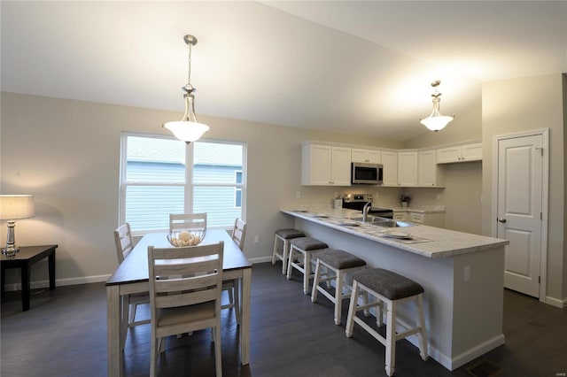 kitchen with white cabinets, decorative light fixtures, kitchen peninsula, and appliances with stainless steel finishes