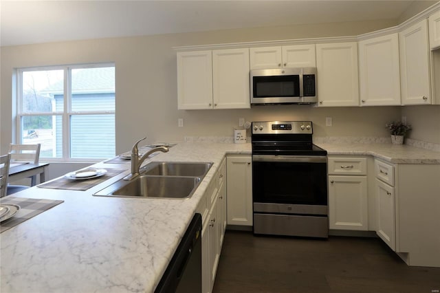 kitchen with dark hardwood / wood-style flooring, stainless steel appliances, white cabinetry, and sink