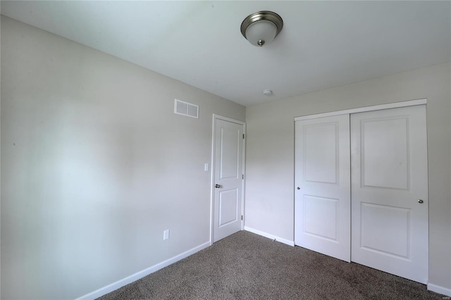 unfurnished bedroom with a closet and dark carpet