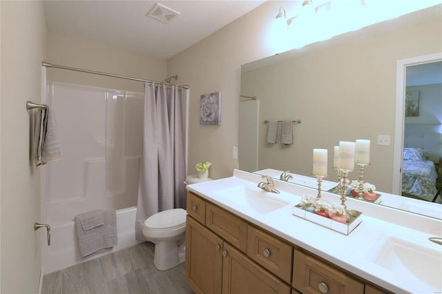 full bathroom featuring hardwood / wood-style floors, vanity, shower / bath combination with curtain, and toilet