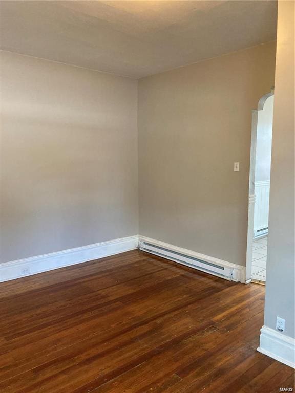 unfurnished room with baseboard heating and dark wood-type flooring