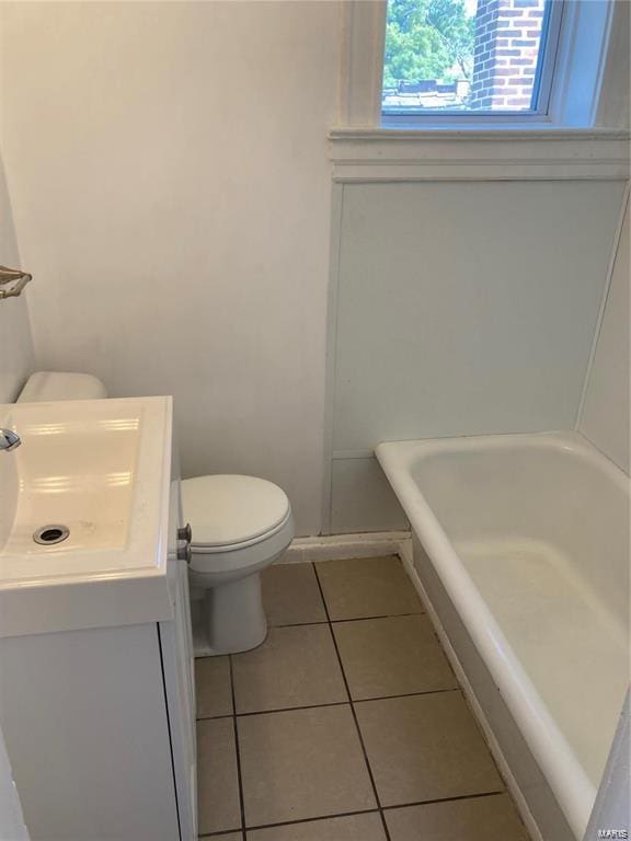 bathroom featuring tile patterned flooring, a bath, vanity, and toilet